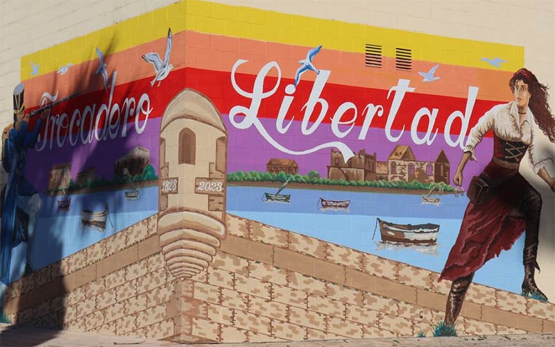 Un mural rememora la Batalla del Trocadero en el paseo marítimo de Puerto Real, y un grafiti homenajea a Agnes Reston en el Río San Pedro
