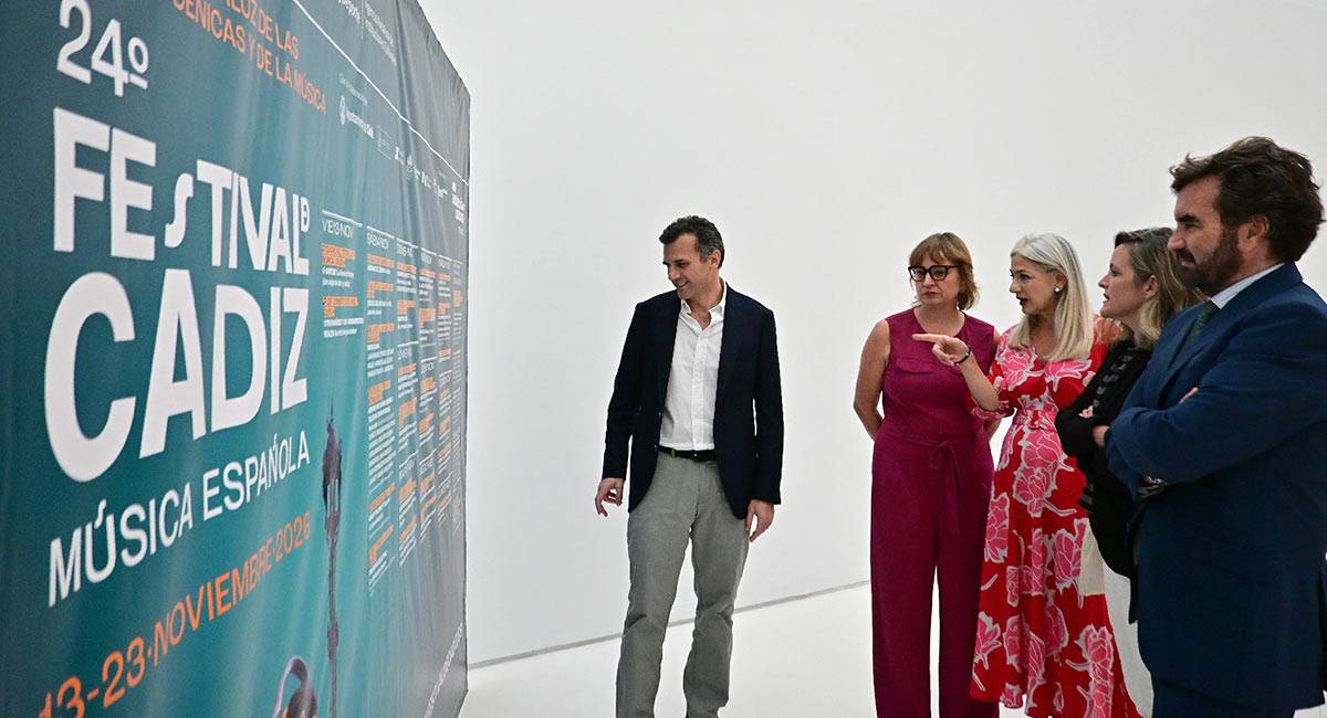 La comitiva alrededor de la consejera repasa la programación en un cartel - Eulogio García